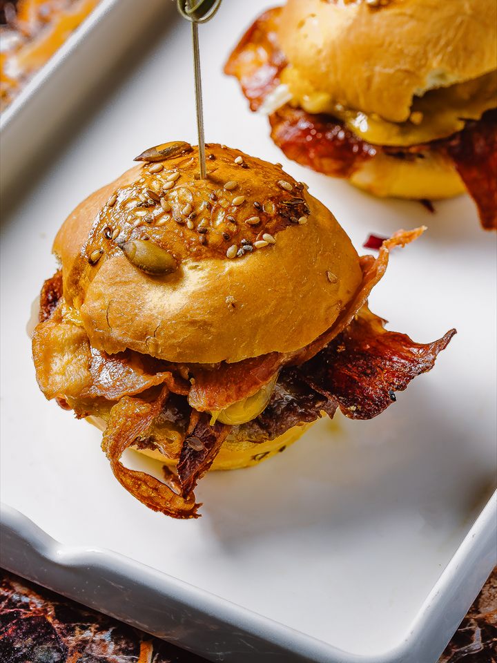 Un mini panino ai semi con bacon croccante su un vassoio bianco